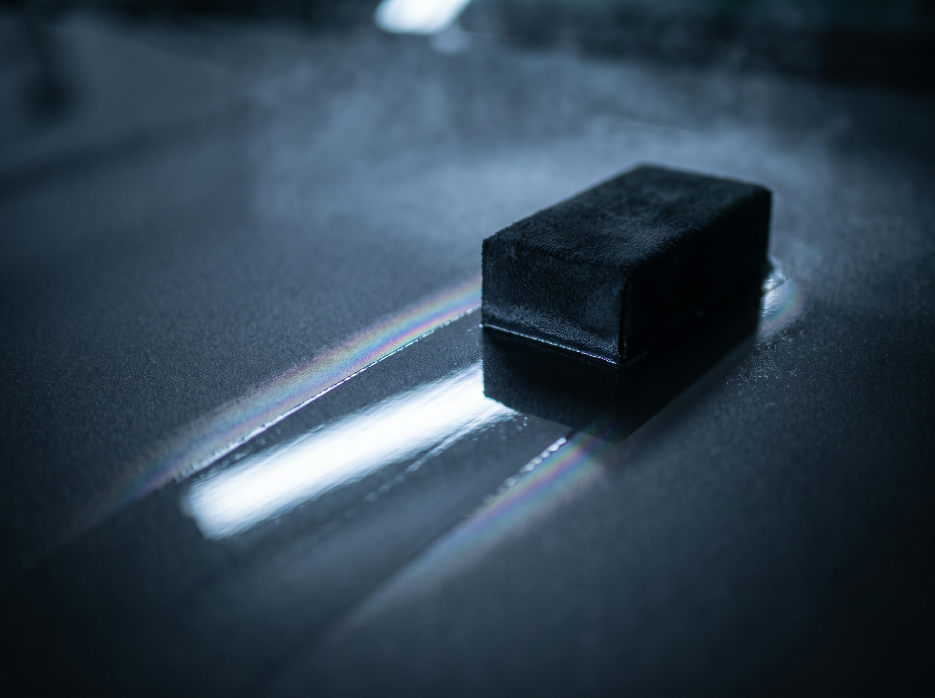 A coating applicator leaving a mirror trail across graphite paint